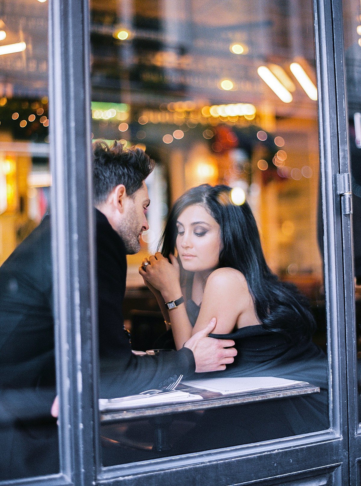 a couple seated at a cafe in paris with an engagement photographer
