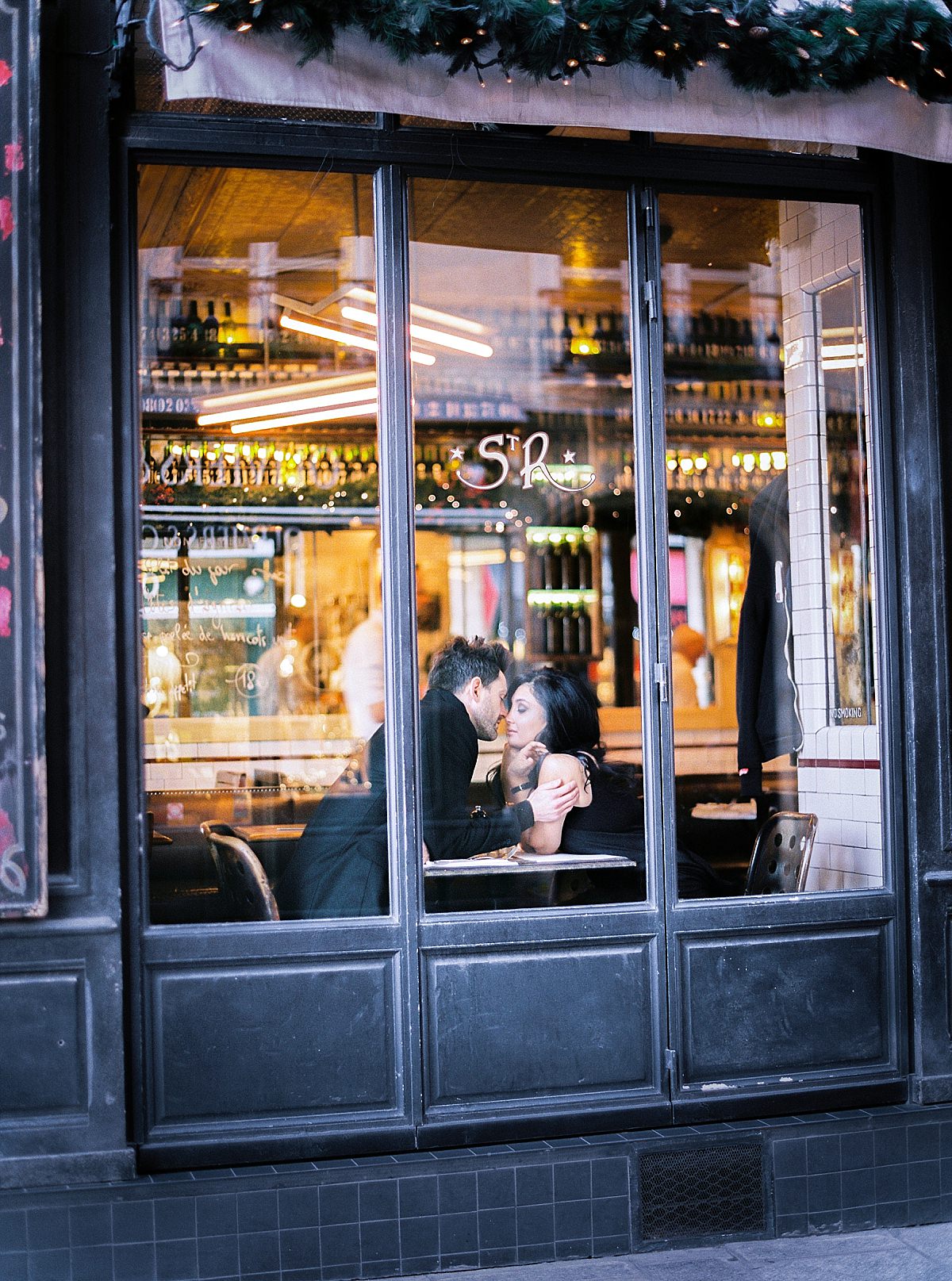 couple kissing in a Paris cafe for their honeymoon
