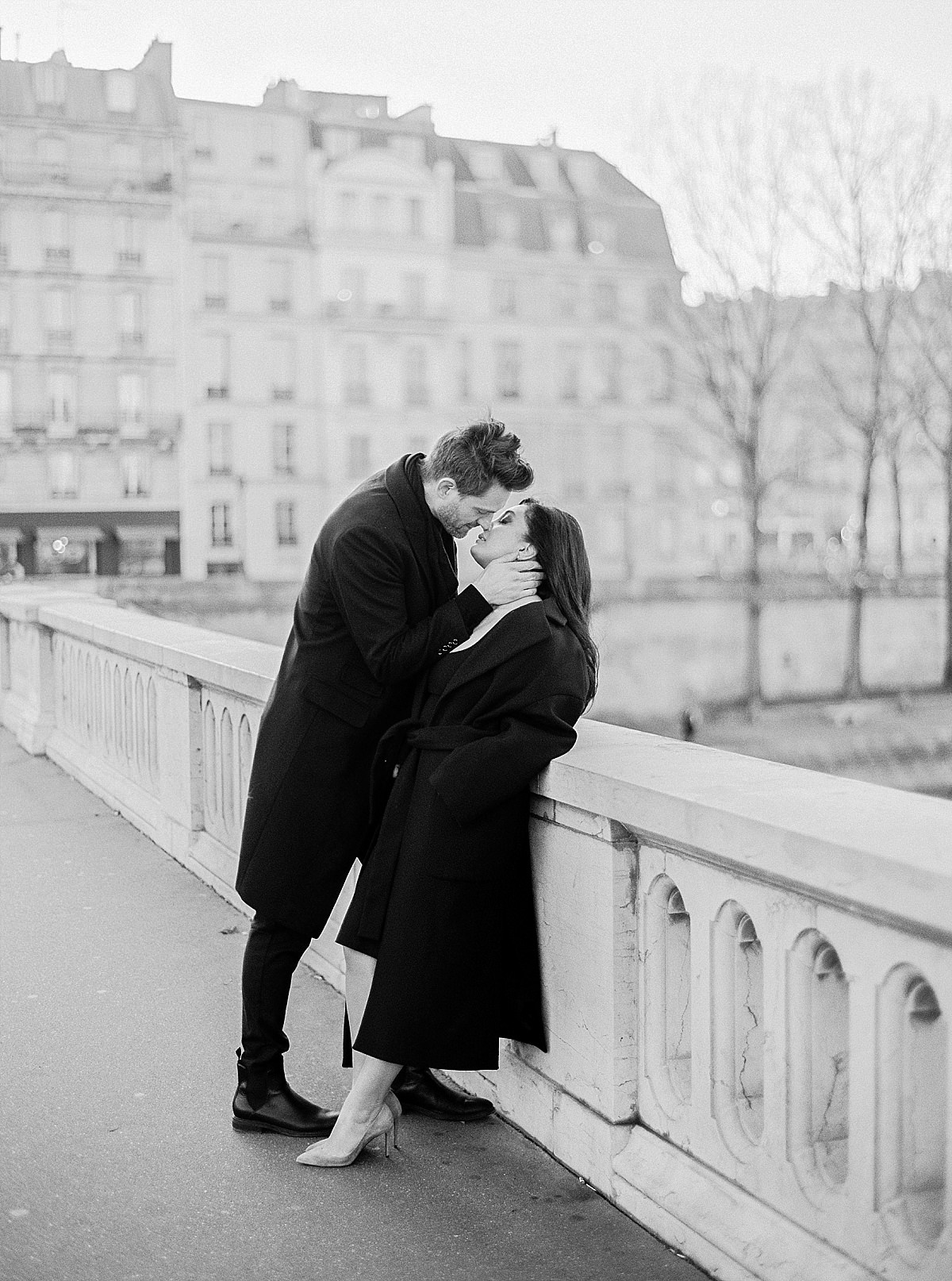 black and white photo of a couple kissing in Paris on a bridge
