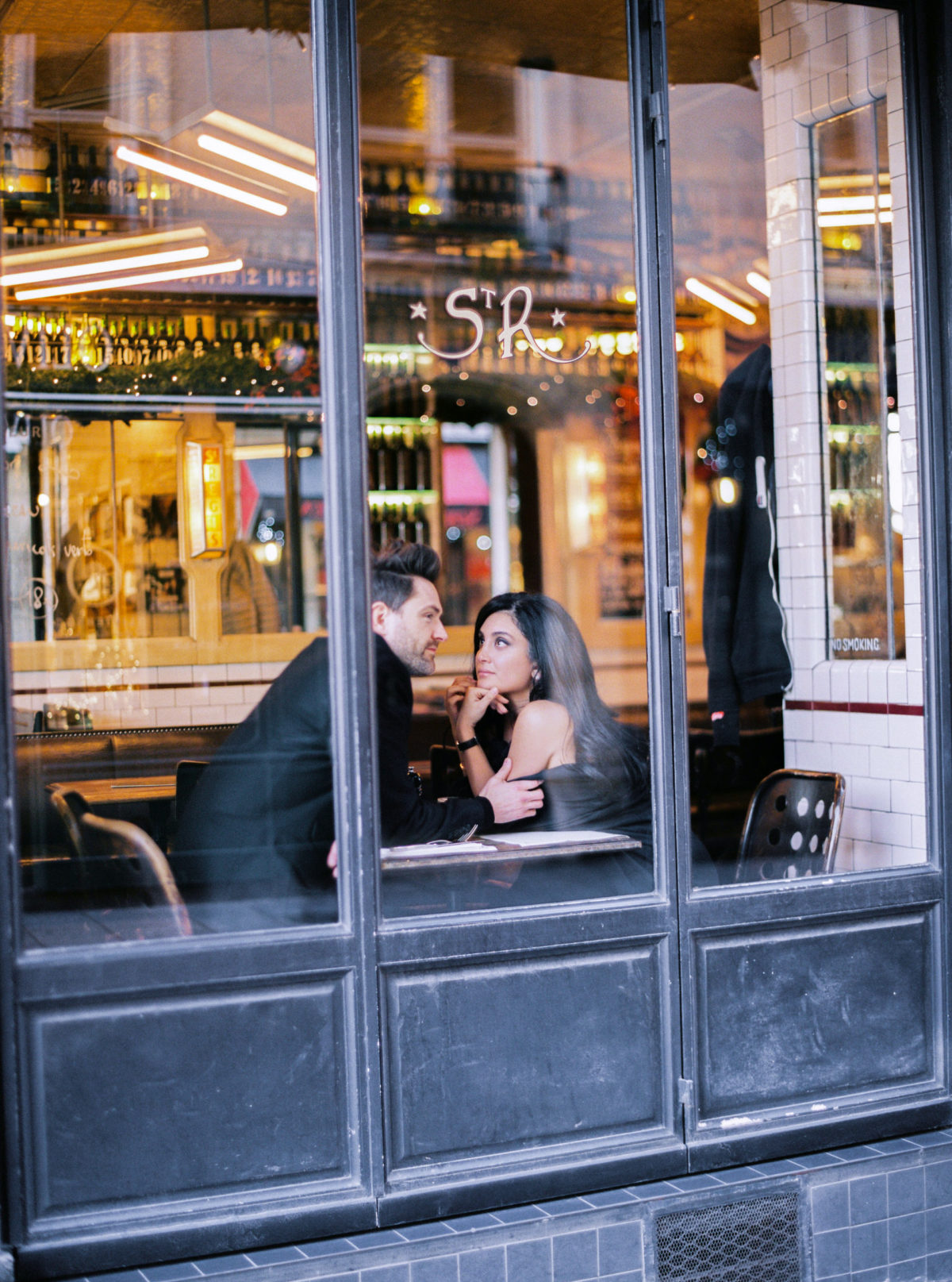 couple at a cafe for their pre wedding photos in paris on ile saint louis cafe saint regis - Le Secret D'Audrey