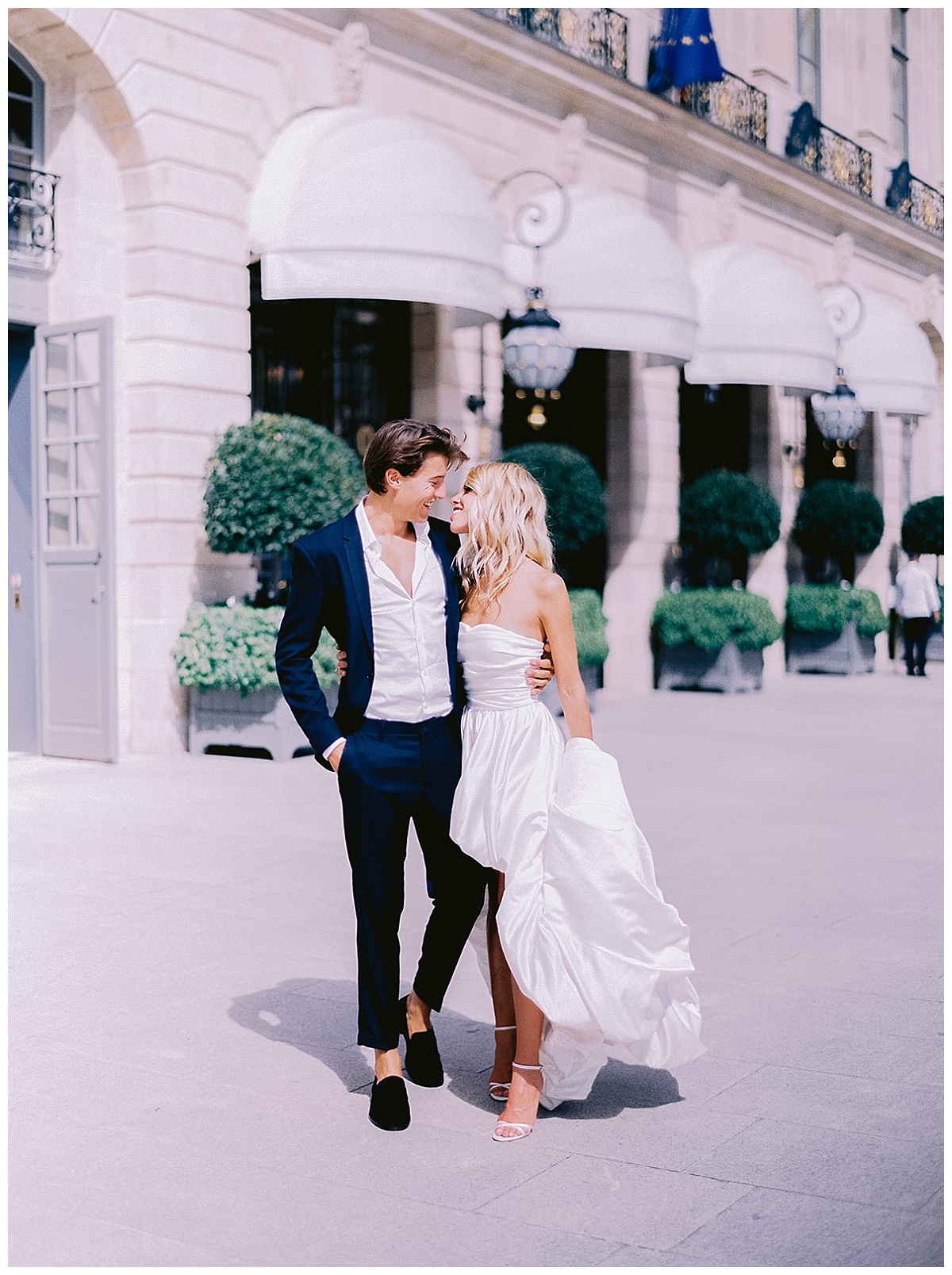 the bride in her white dress and the groom walk out the ritz, 