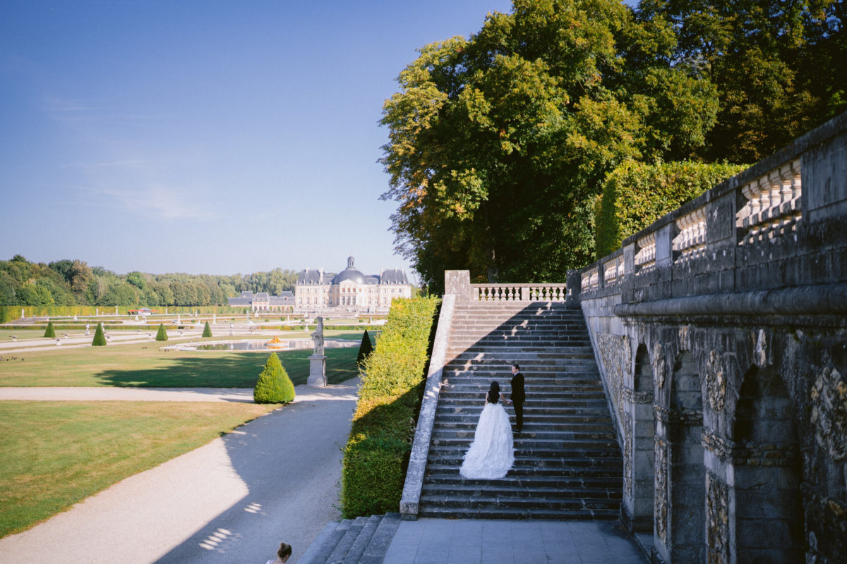 The brie and the groom on the stairs of the Chateau de Vaux el Vicomte 
